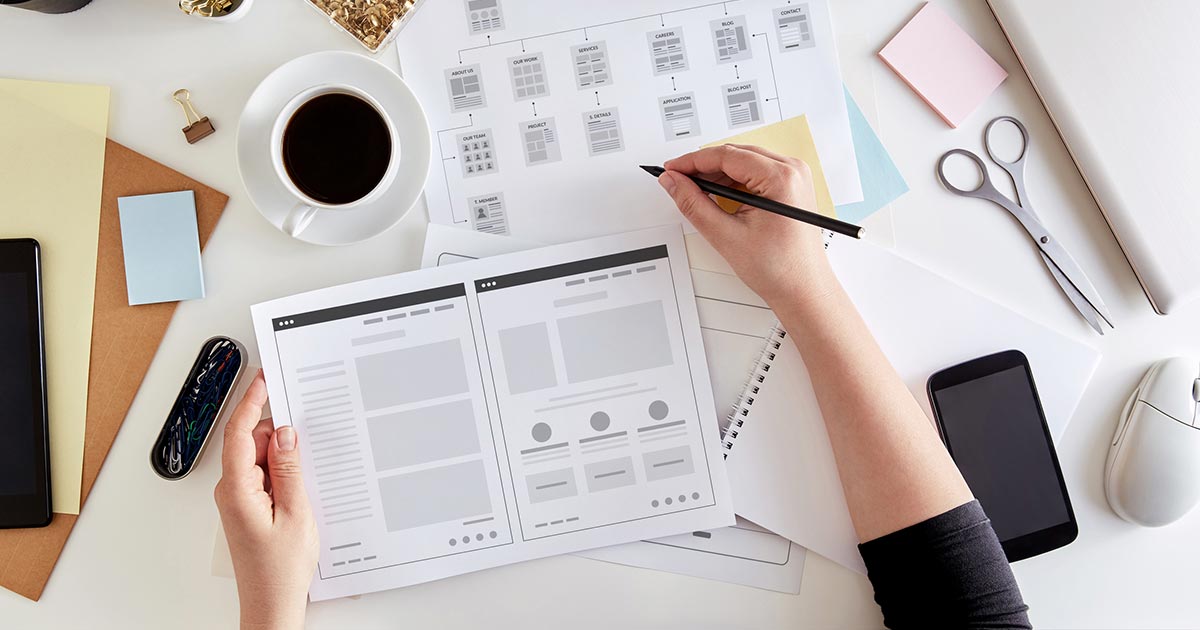 Person planning out a website with pen and paper.