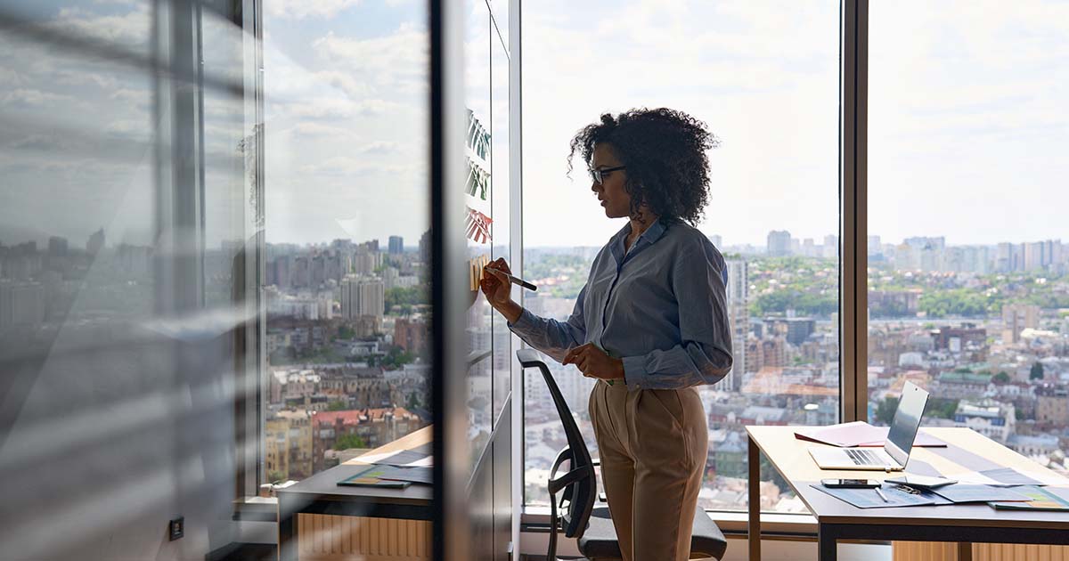 A woman writing on post it notes on the wall.