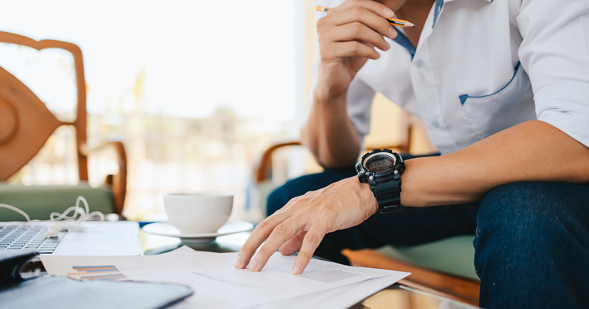 A man doing paperwork with a laptop.