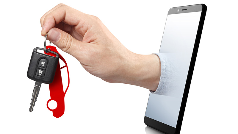 A hand sticking out of a smartphone screen holding car keys.