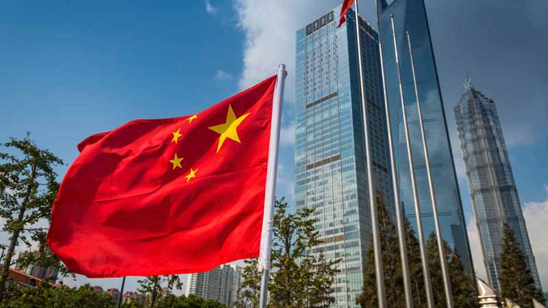 Chinese flag flying next to skyscrapers in Shanghai.