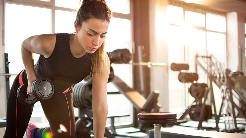 A woman lifting dumbbells at the gym.