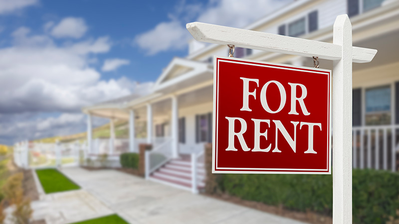 A For Rent sign in front of a house.
