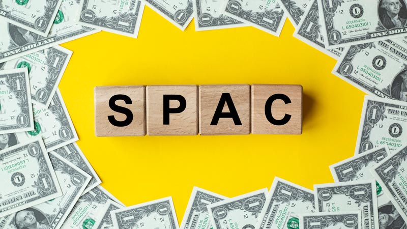 Wooden blocks spelling SPAC surrounded by money.