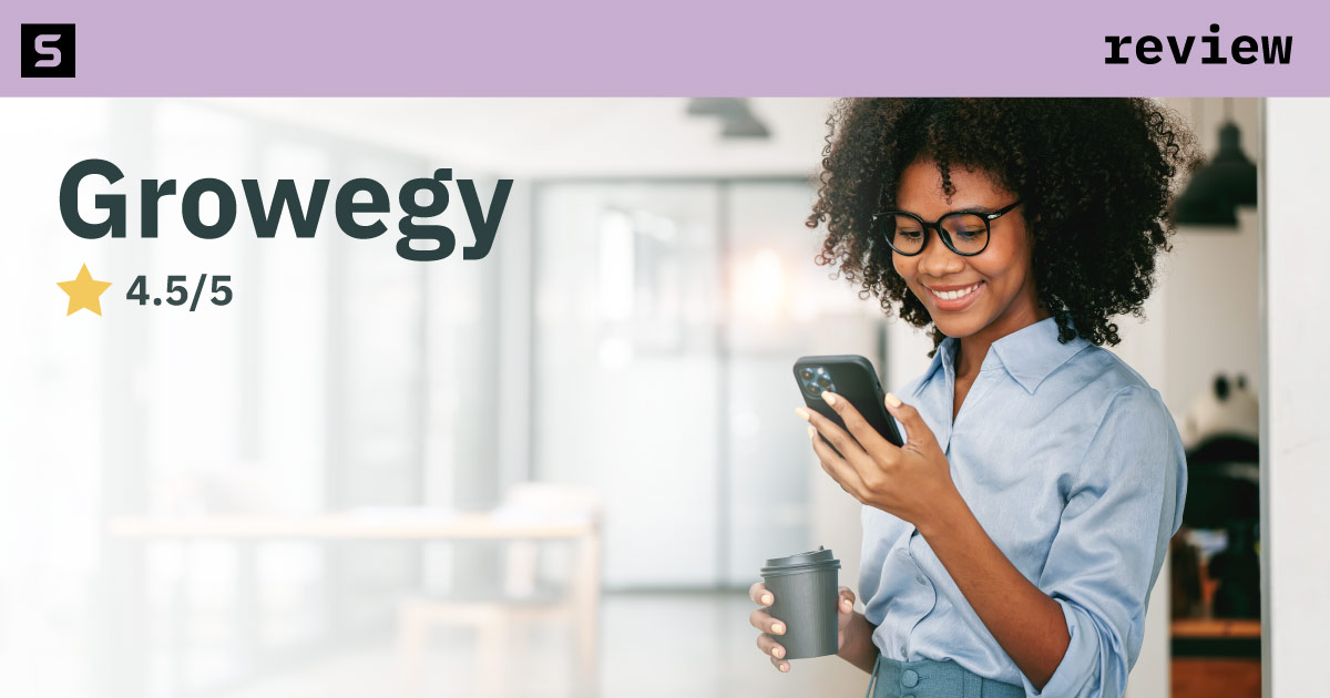 Smiling woman holding a coffee cup and using her phone.