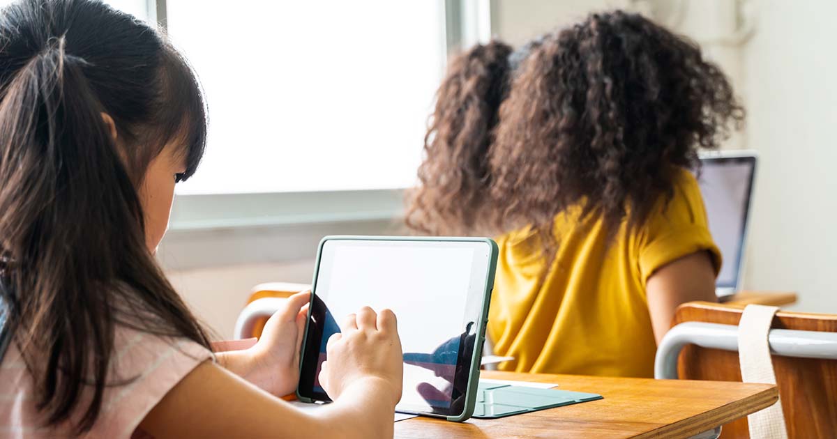 Children using digital devices in classroom.