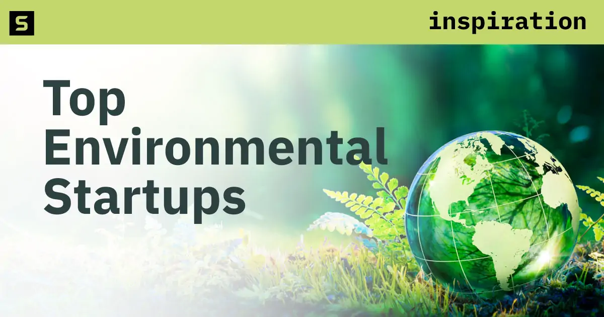 Hand holding light bulb with a background of blurred green trees.