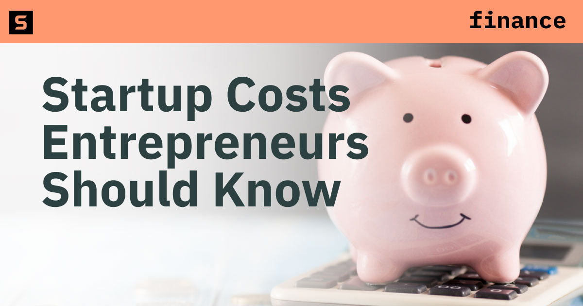 Piggy bank on a calculator next to coins.